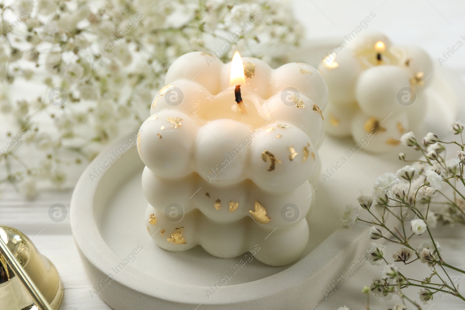 Photo of Stylish bubble candles and gypsophila flowers on white wooden table, closeup