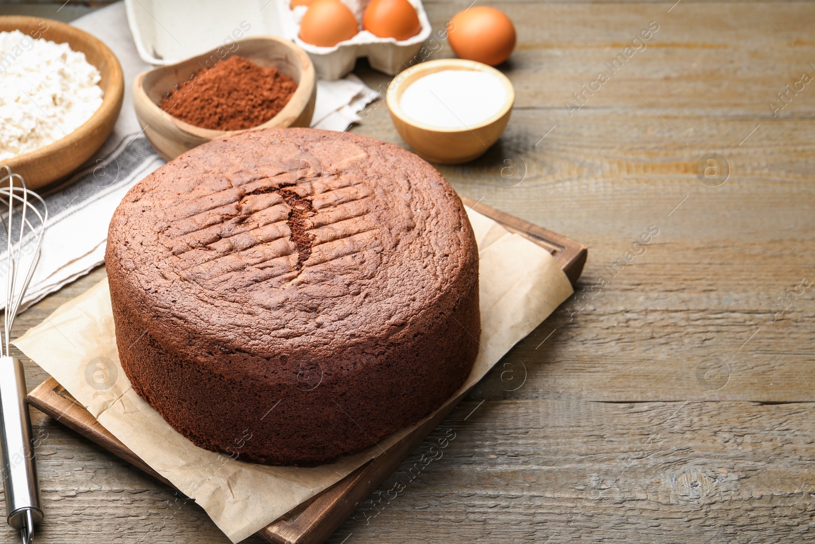 Photo of Tasty chocolate sponge cake and ingredients on wooden table