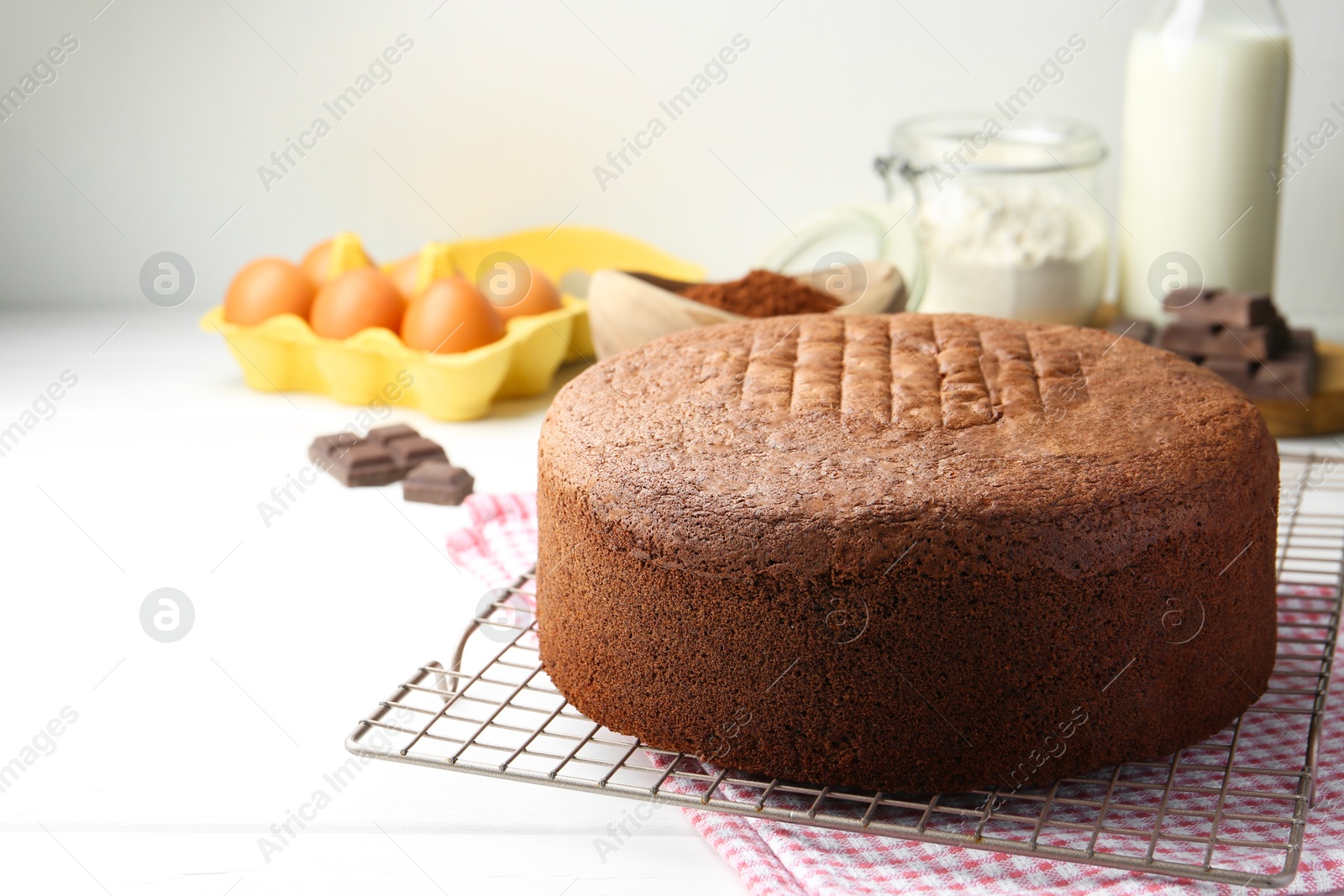 Photo of Tasty chocolate sponge cake and ingredients on white wooden table