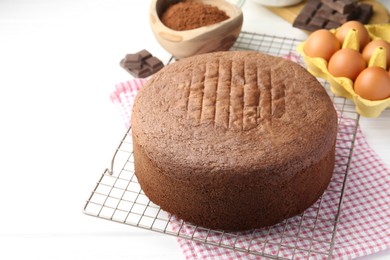 Photo of Tasty chocolate sponge cake and ingredients on white wooden table, closeup