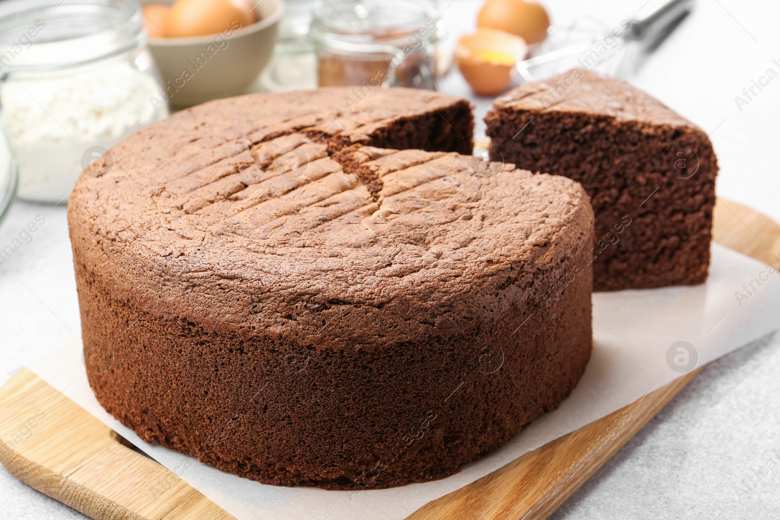 Photo of Cut chocolate sponge cake on light table, closeup