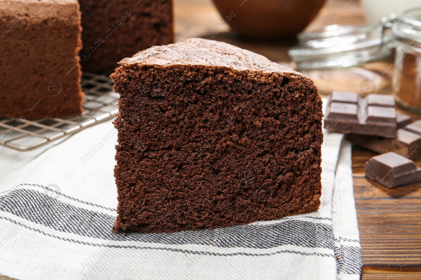 Photo of Piece of tasty chocolate sponge cake on wooden table, closeup