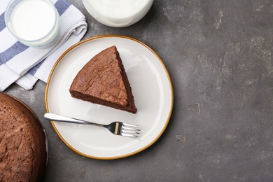 Photo of Piece of tasty chocolate sponge cake served on grey table, flat lay