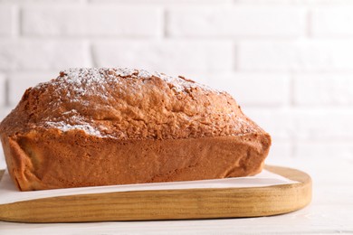 Photo of Tasty sponge cake with powdered sugar on white table, closeup