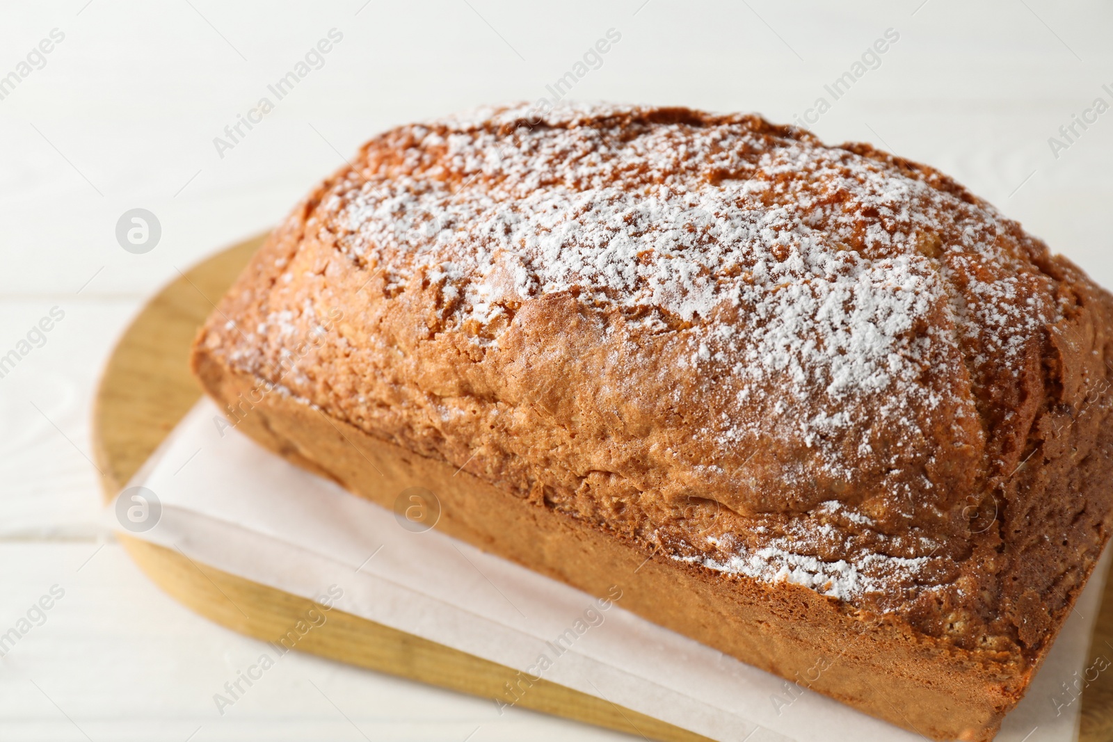 Photo of Tasty sponge cake with powdered sugar on white table, closeup