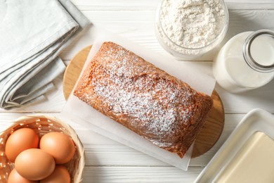 Photo of Tasty sponge cake with ingredients on white wooden table, flat lay