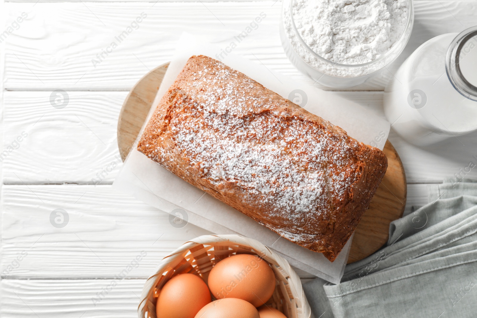 Photo of Tasty sponge cake with ingredients on white wooden table, flat lay