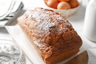 Photo of Tasty sponge cake with ingredients on white table, closeup