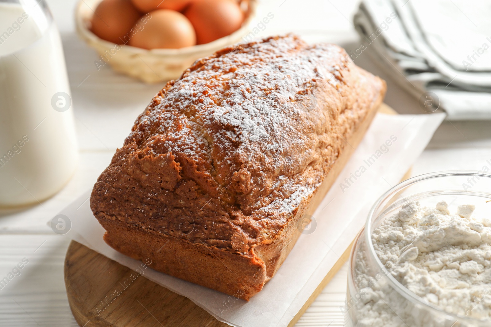 Photo of Tasty sponge cake with ingredients on white table, closeup