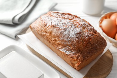 Photo of Tasty sponge cake with ingredients on white table, closeup