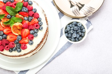 Photo of Delicious chocolate sponge cake with berries served on light table, flat lay