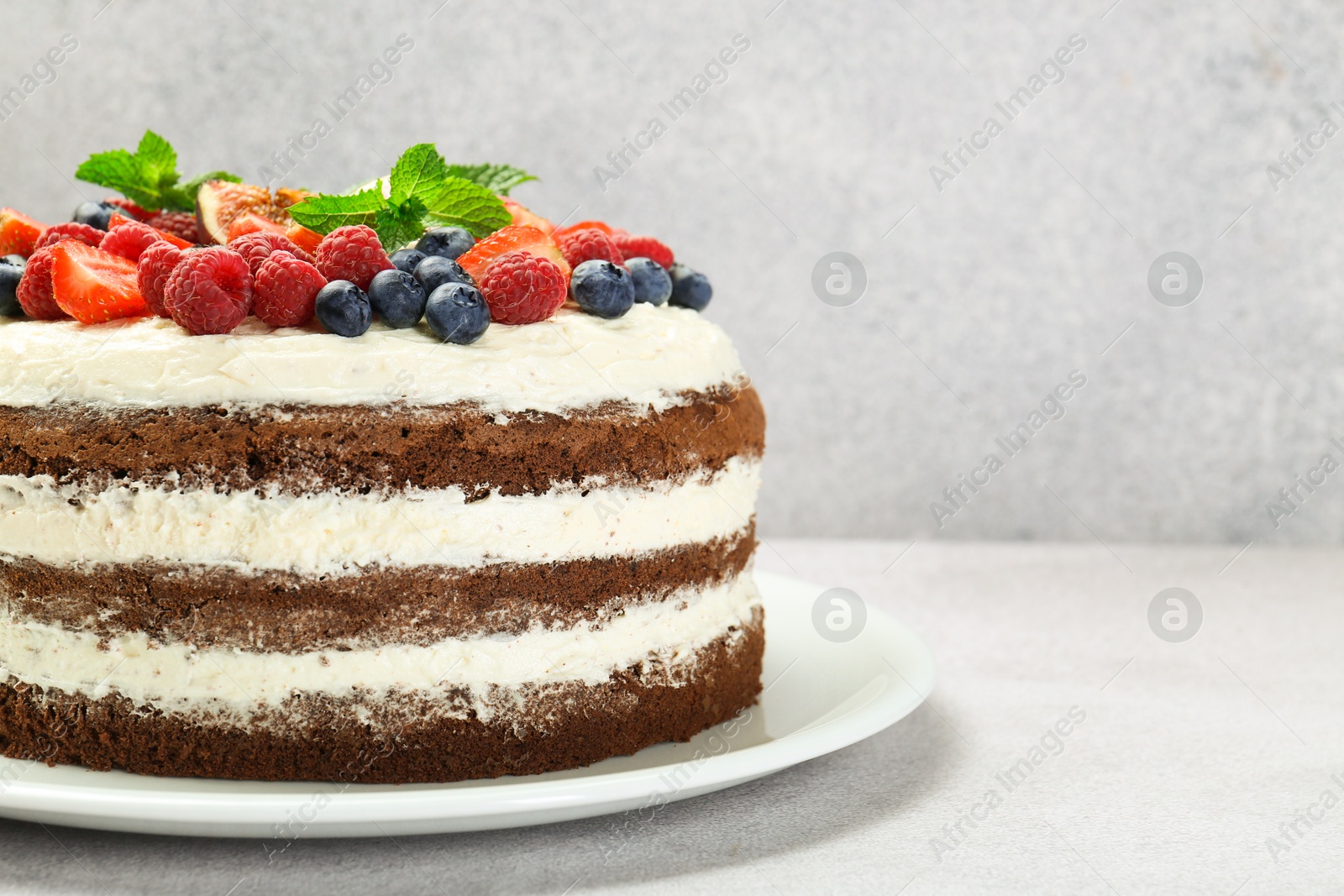 Photo of Delicious chocolate sponge cake with berries on light table, closeup. Space for text