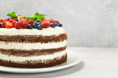 Delicious chocolate sponge cake with berries on light table, closeup. Space for text