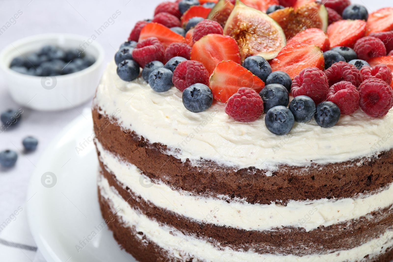 Photo of Delicious chocolate sponge cake with berries on light table, closeup