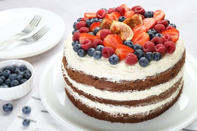 Delicious chocolate sponge cake with berries served on light table, closeup