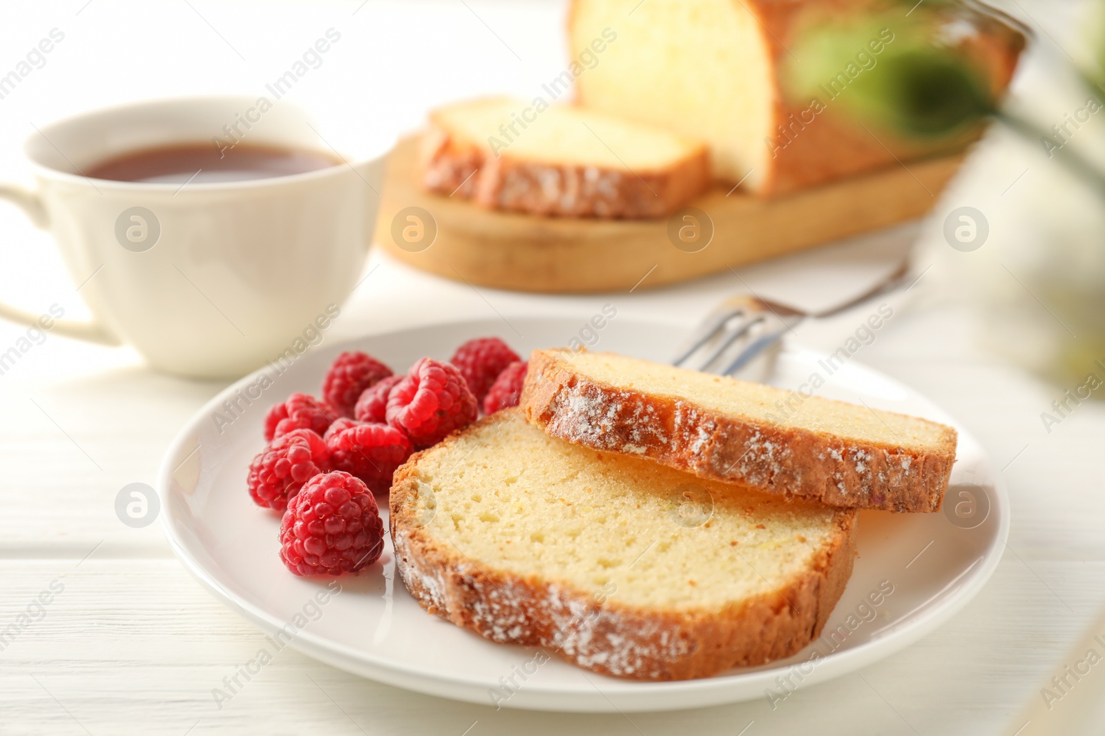 Photo of Freshly baked sponge cake and raspberries on white wooden table