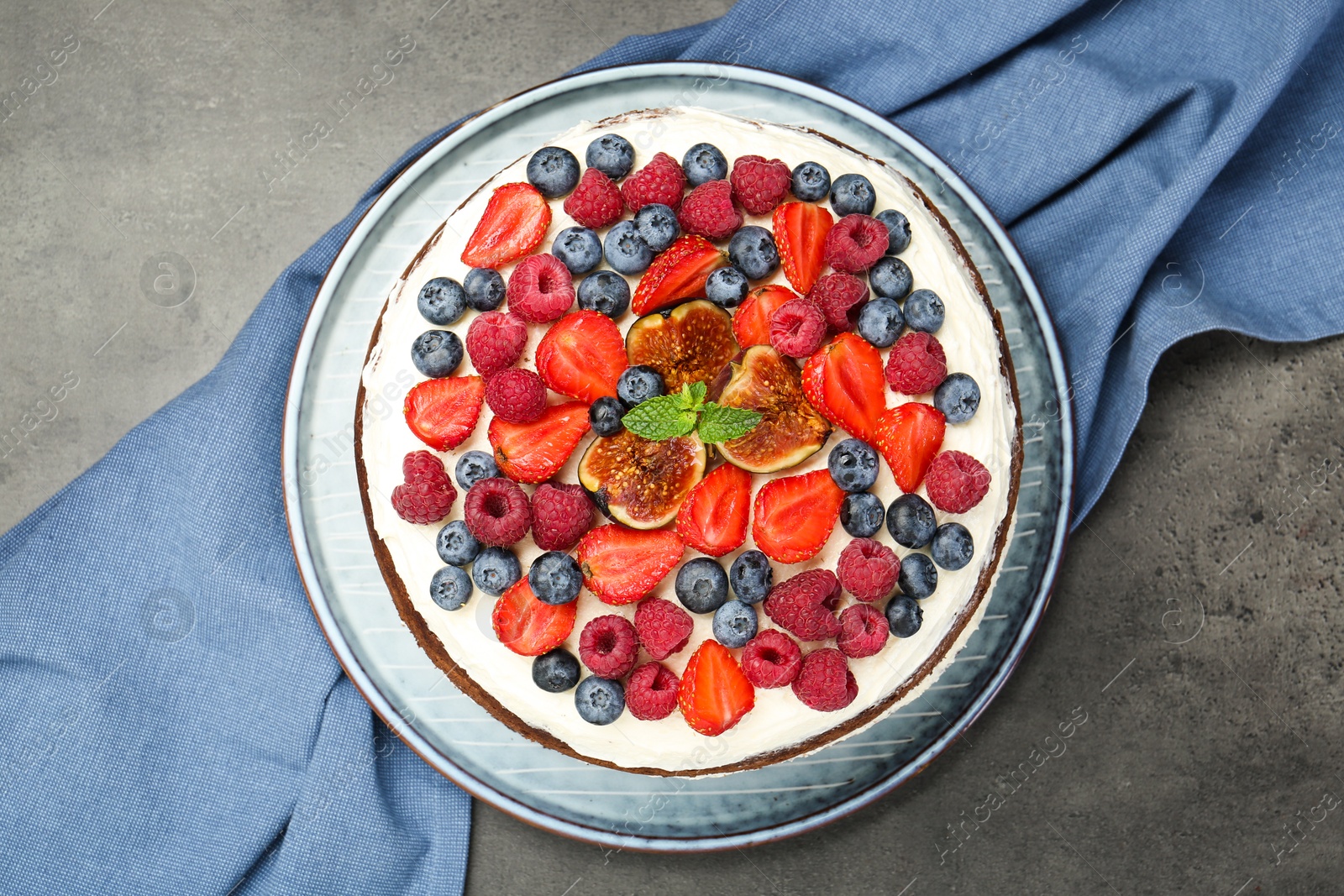 Photo of Delicious chocolate sponge cake with berries on grey table, top view