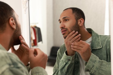 Worried man looking at mirror at home