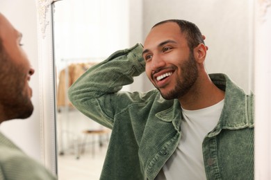 Photo of Smiling man looking at mirror at home