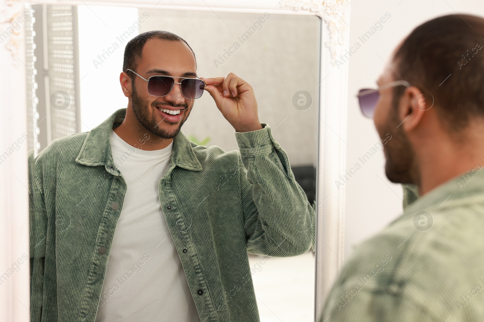 Photo of Smiling man looking at mirror at home