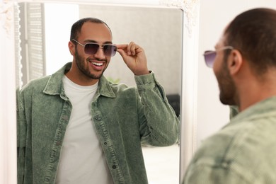 Photo of Smiling man looking at mirror at home