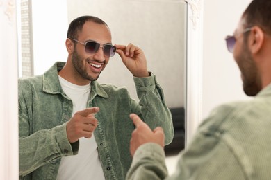 Photo of Smiling man looking at mirror at home