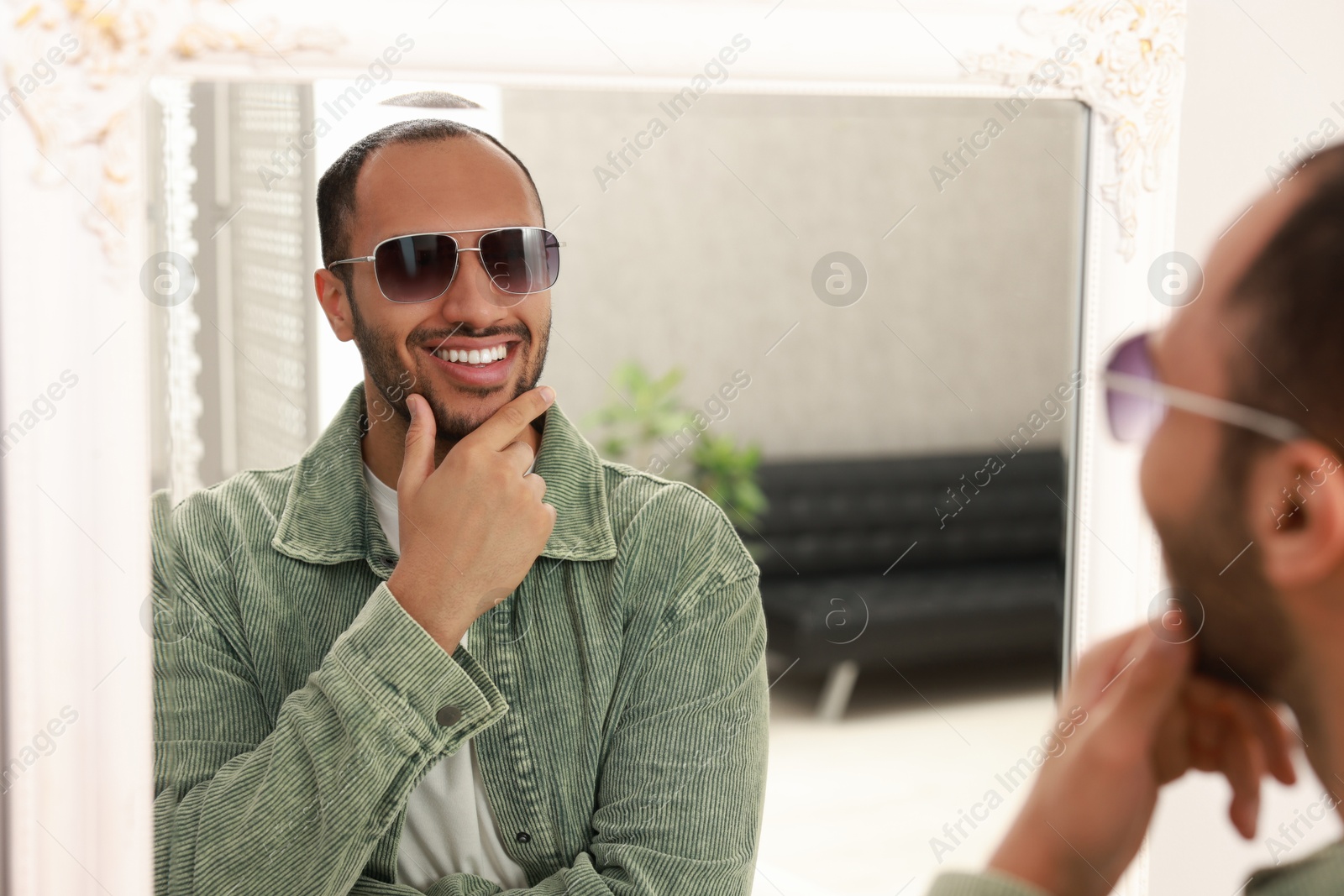 Photo of Smiling man looking at mirror at home