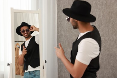 Photo of Smiling man looking at mirror at home