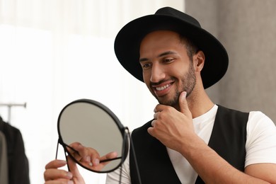 Photo of Smiling man looking at mirror at home