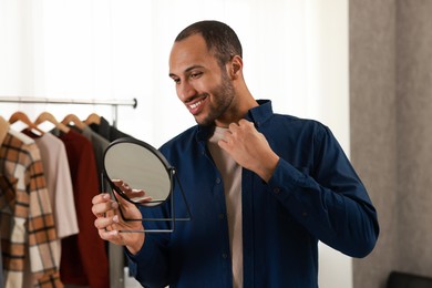 Photo of Smiling man looking at mirror at home