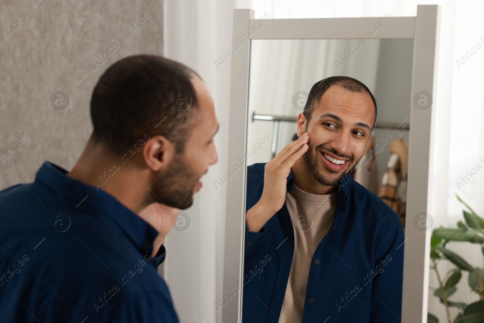 Photo of Smiling man looking at mirror at home