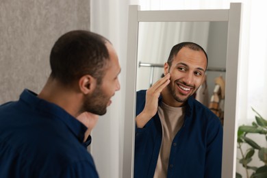 Photo of Smiling man looking at mirror at home