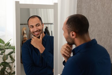 Photo of Smiling man looking at mirror at home