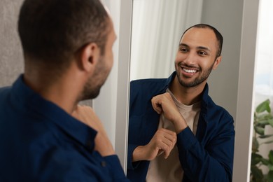 Photo of Smiling man looking at mirror at home