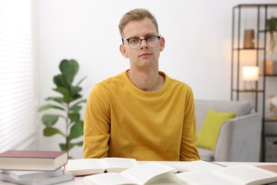 Photo of Preparing for exam. Student with books at table indoors