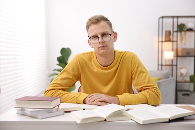 Photo of Preparing for exam. Student with books at table indoors