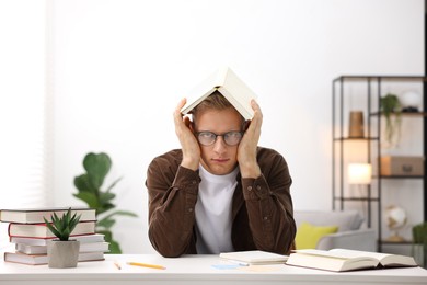 Photo of Preparing for exam. Student with book at table indoors