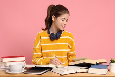 Photo of Student preparing for exam at table against pink background