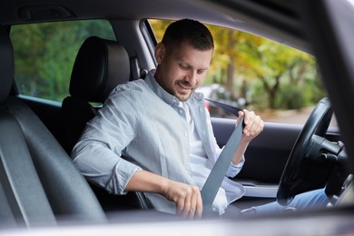 Photo of Man fastening seat belt in modern car