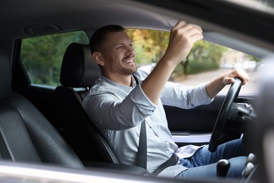 Photo of Man adjusting rear-view mirror in car before driving