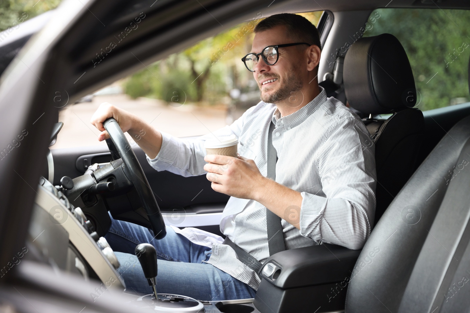 Photo of Man with cup of coffee driving modern car