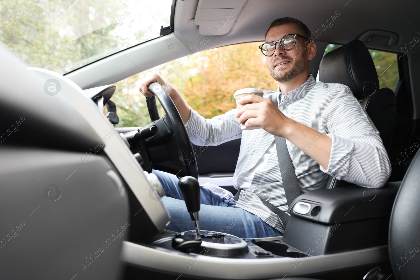 Photo of Man with coffee driving modern car, low angle view