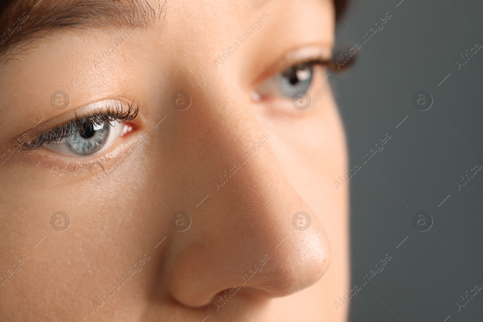 Photo of Young woman with beautiful blue eyes on grey background, closeup