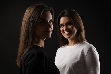 Photo of Portrait of beautiful twin sisters on black background