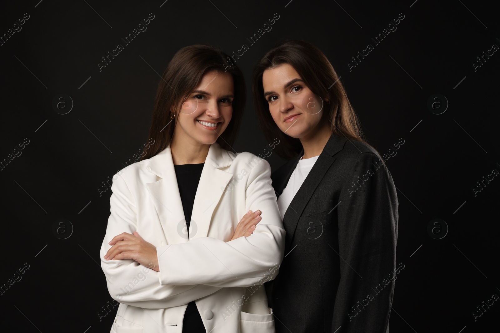 Photo of Portrait of beautiful twin sisters on black background