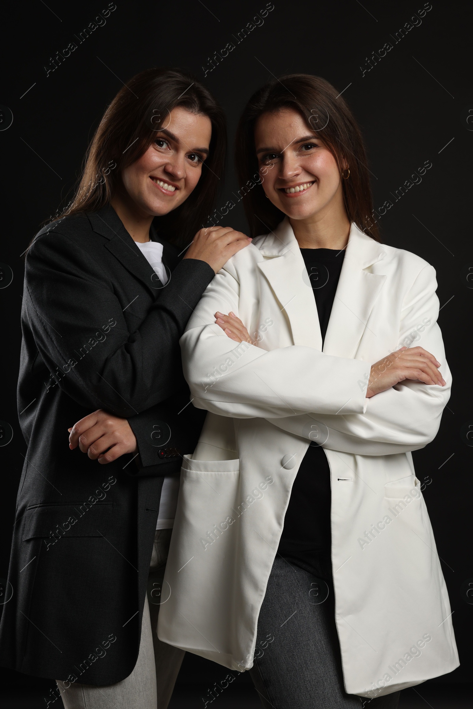 Photo of Portrait of beautiful twin sisters on black background