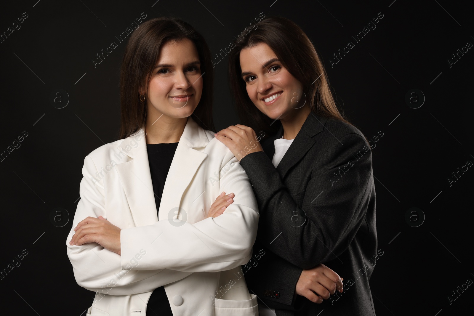 Photo of Portrait of beautiful twin sisters on black background