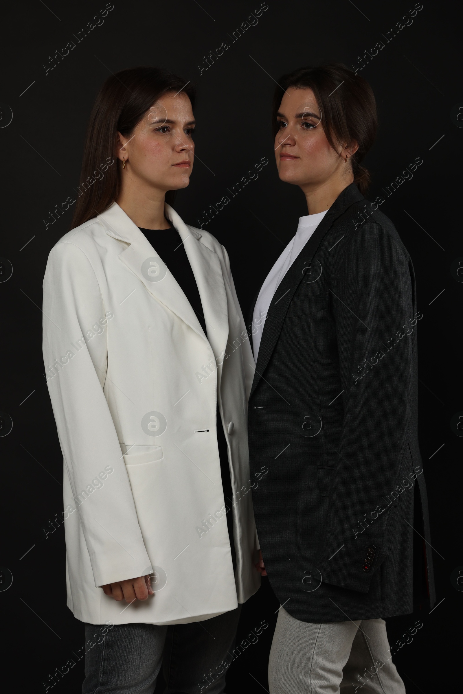 Photo of Portrait of beautiful twin sisters on black background