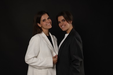 Photo of Portrait of beautiful twin sisters on black background