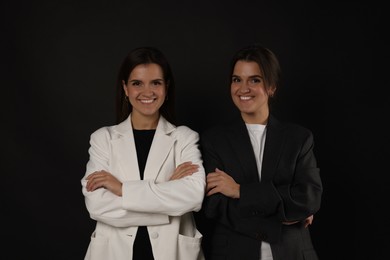 Photo of Portrait of beautiful twin sisters on black background